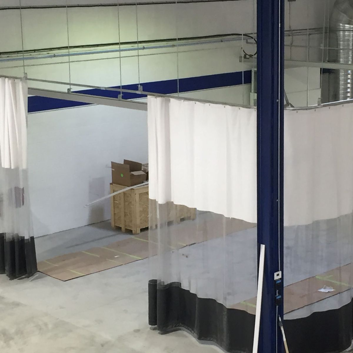 White curtains partially enclose a workspace with boxes and a wooden crate inside.