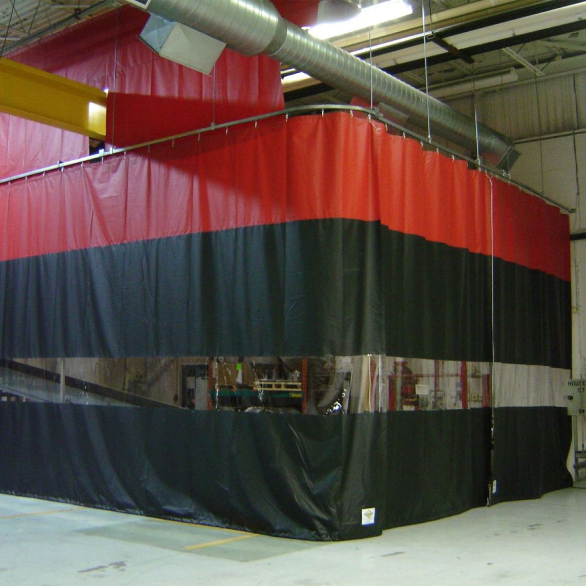 Red, black, and clear industrial curtain enclosure within a warehouse setting.