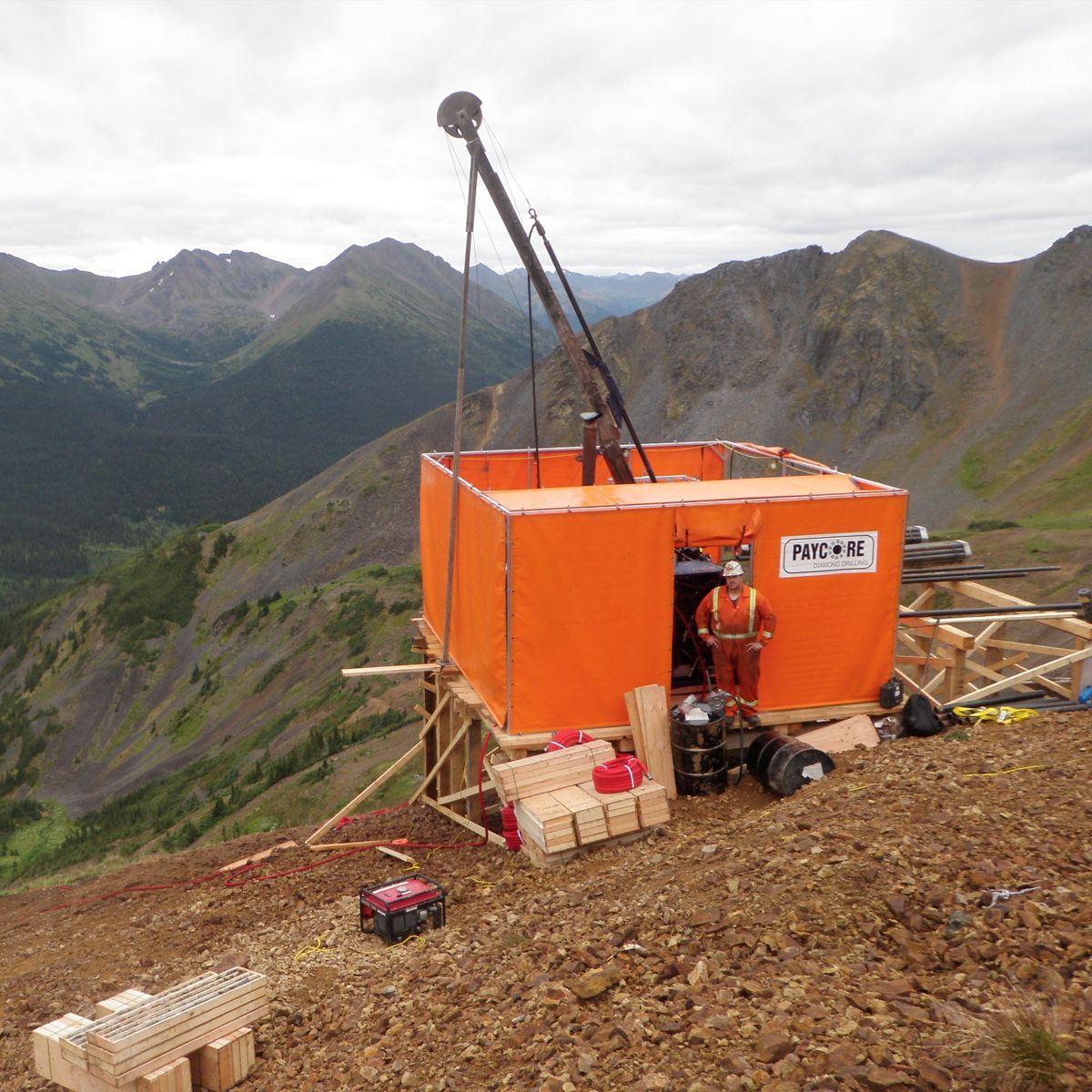 Orange structure with drilling equipment on a mountain, person in orange suit.