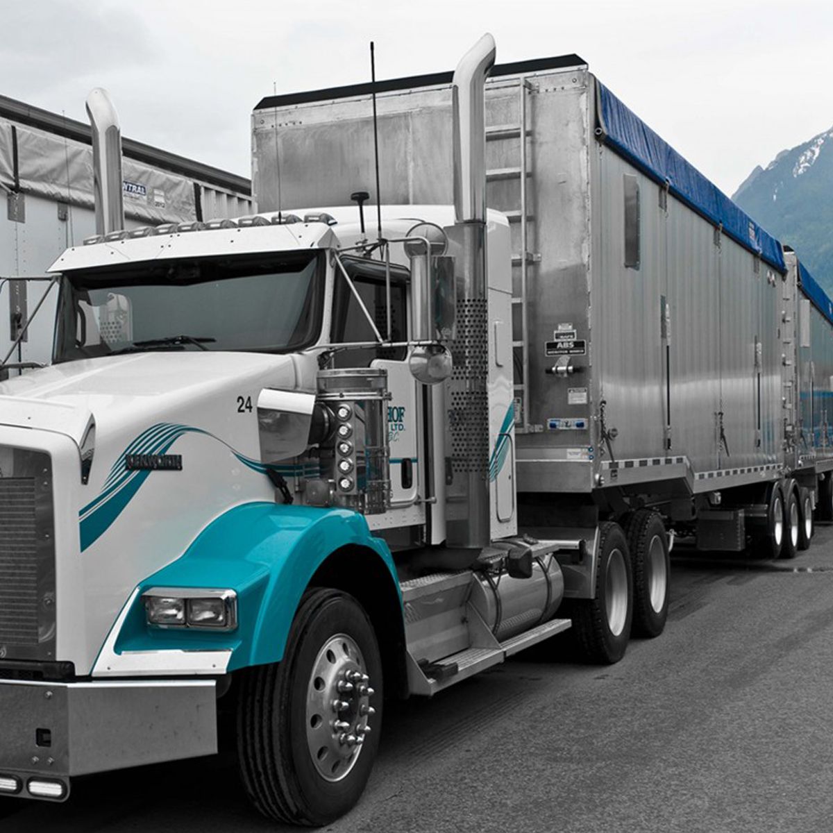 White semi-truck with blue accents and a covered trailer parked outdoors.