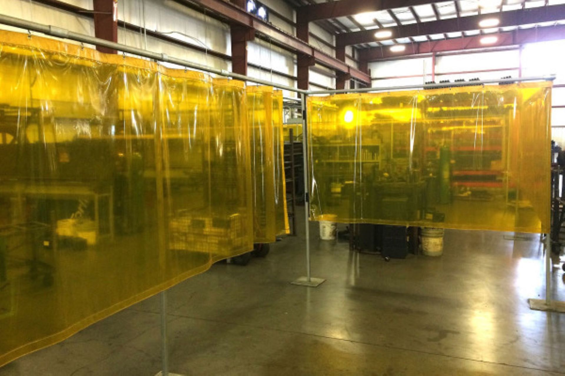 Yellow welding curtains installed in a large workshop, providing protective barriers.