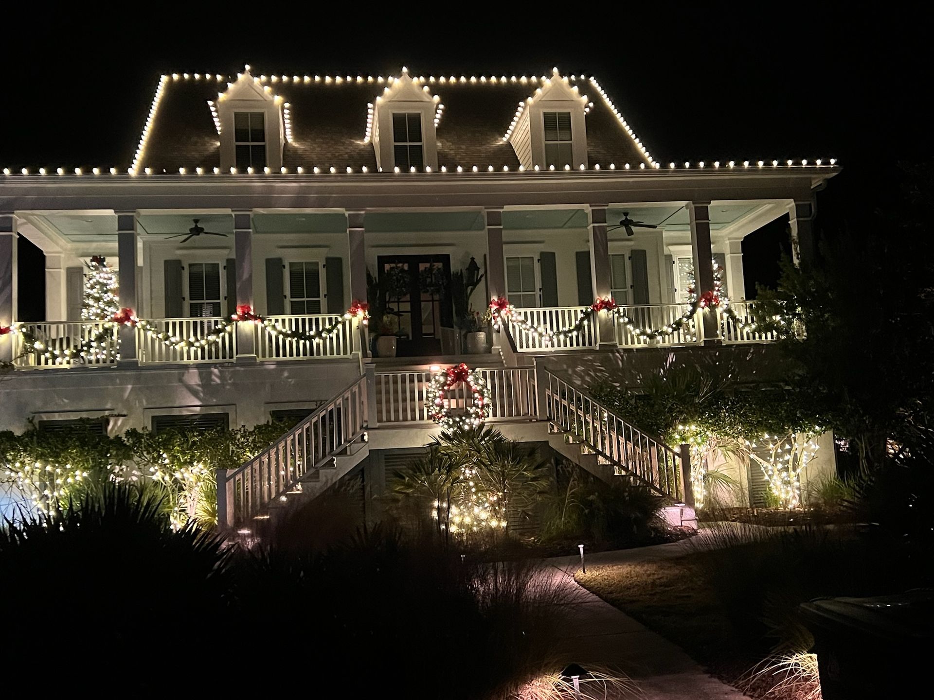 House at night decorated with white Christmas lights and garland.