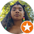 Portrait of a woman outdoors, wearing colorful earrings, with an orange star badge in the corner
