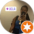 Person taking a mirror selfie, wearing a blue tank top, with a UCLA sticker and orange star icon overlay.