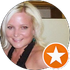 Smiling blonde woman in a black top, with an orange star badge in the corner