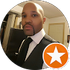 Profile photo of a person in a black suit and tie, holding a phone, with an orange star badge overlay.