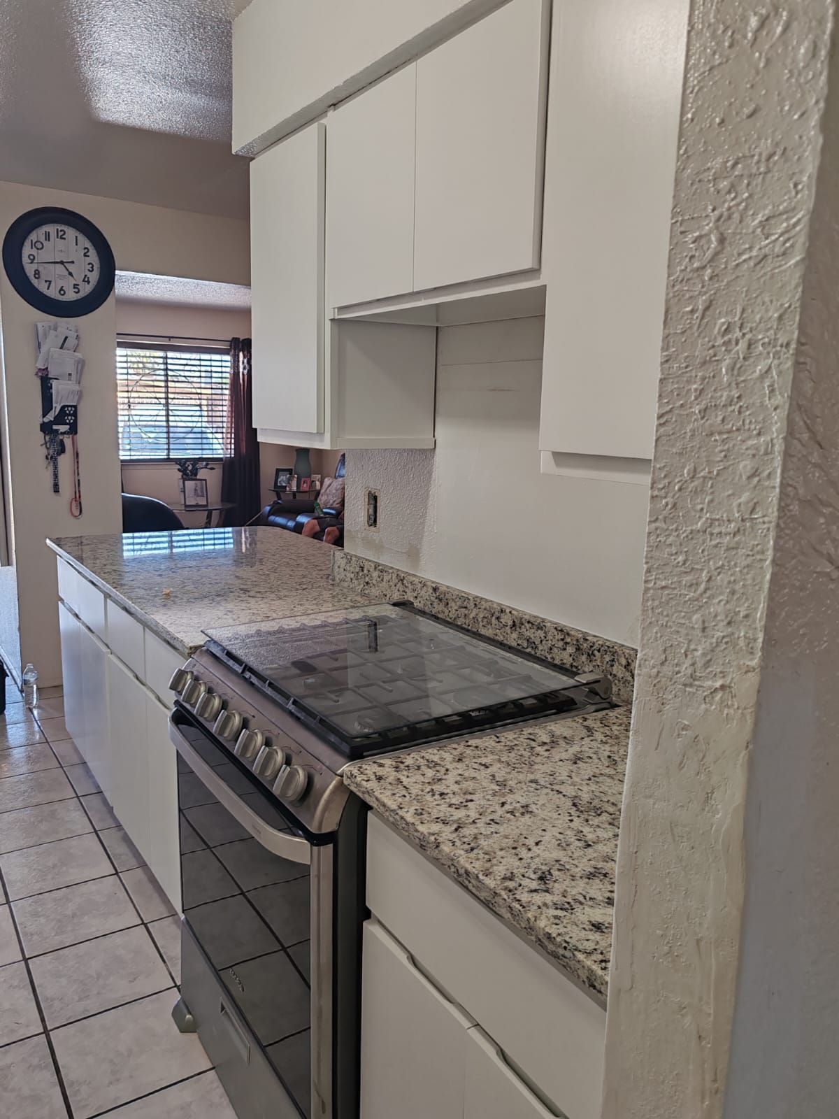 A kitchen with white cabinets and a stove top oven