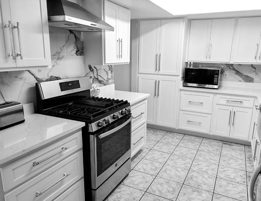 A black and white photo of a kitchen with stainless steel appliances and white cabinets.