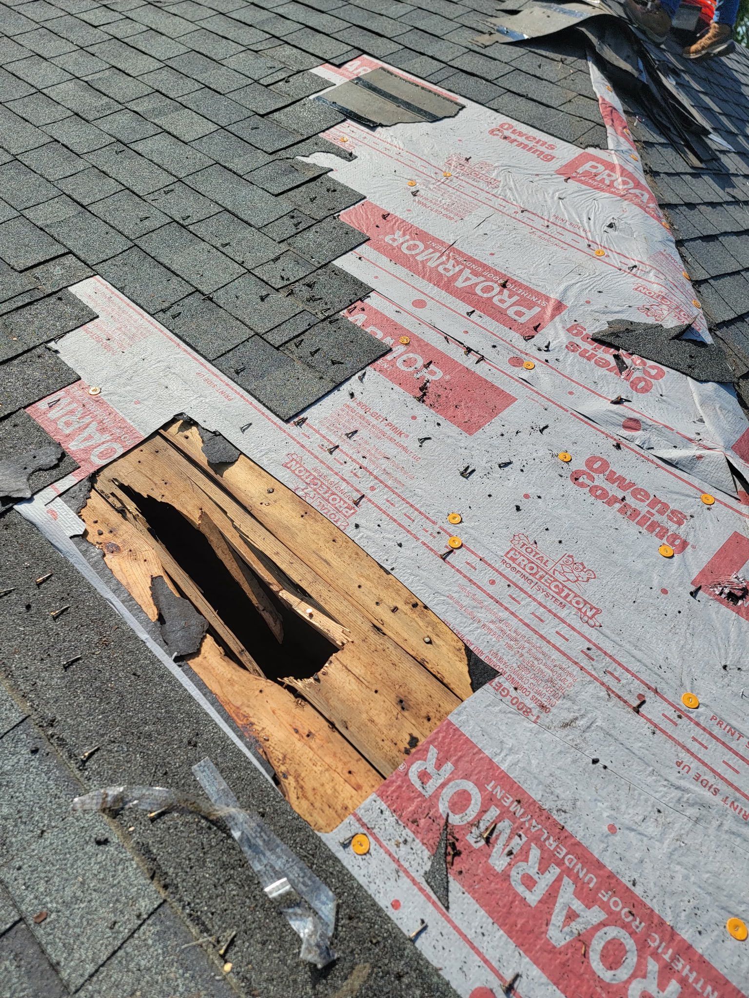 Roof with missing shingles, exposed underlayment and damaged wood.