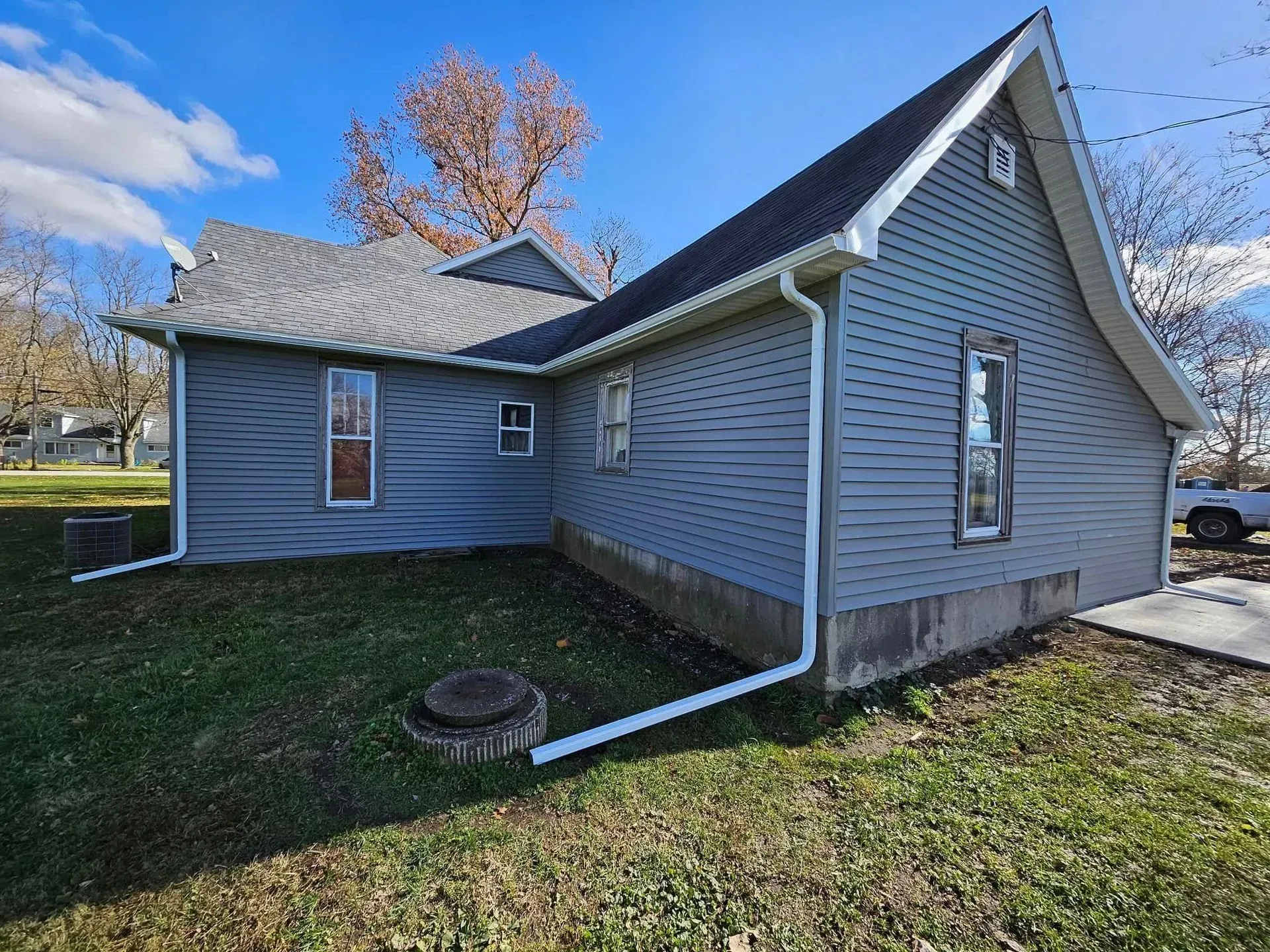 Gray house with a dark roof and white trim, on a grassy lot.