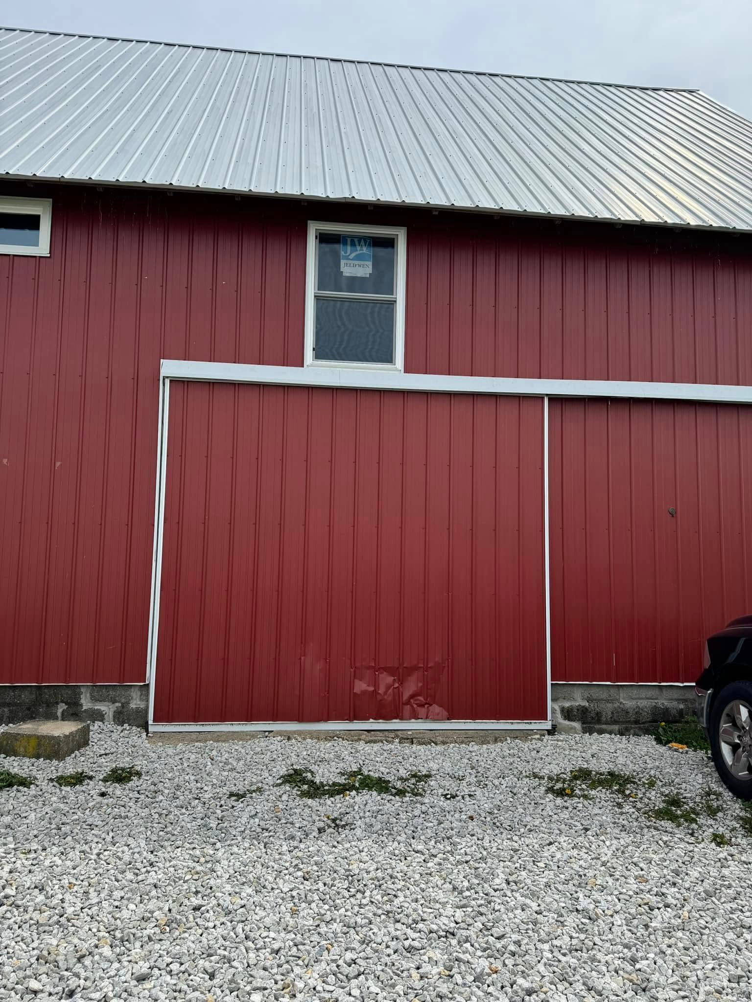 Person installing a door, standing on a ladder. Exterior view of a building with light-colored siding.