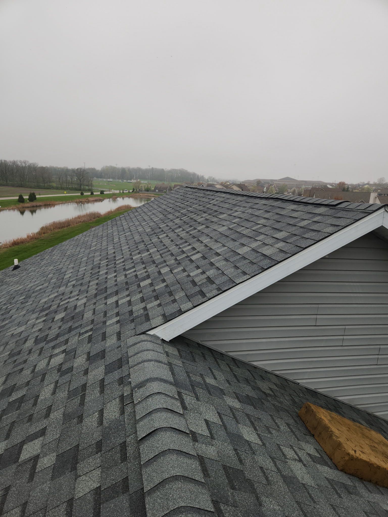 Close-up of a weathered shingle roof with missing shingles. A light-colore