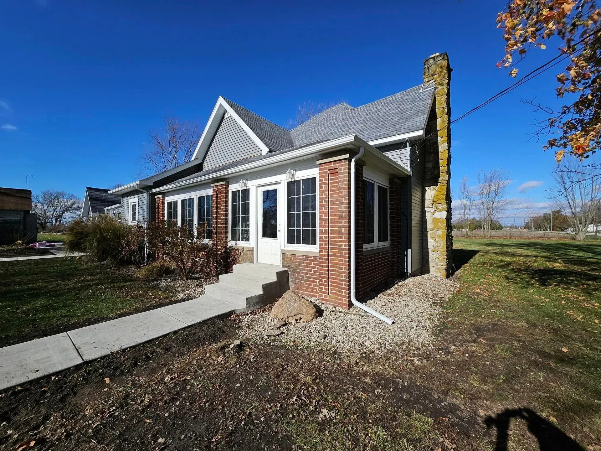 A single-story house with a brick facade and a chimney stands under a blue sky.