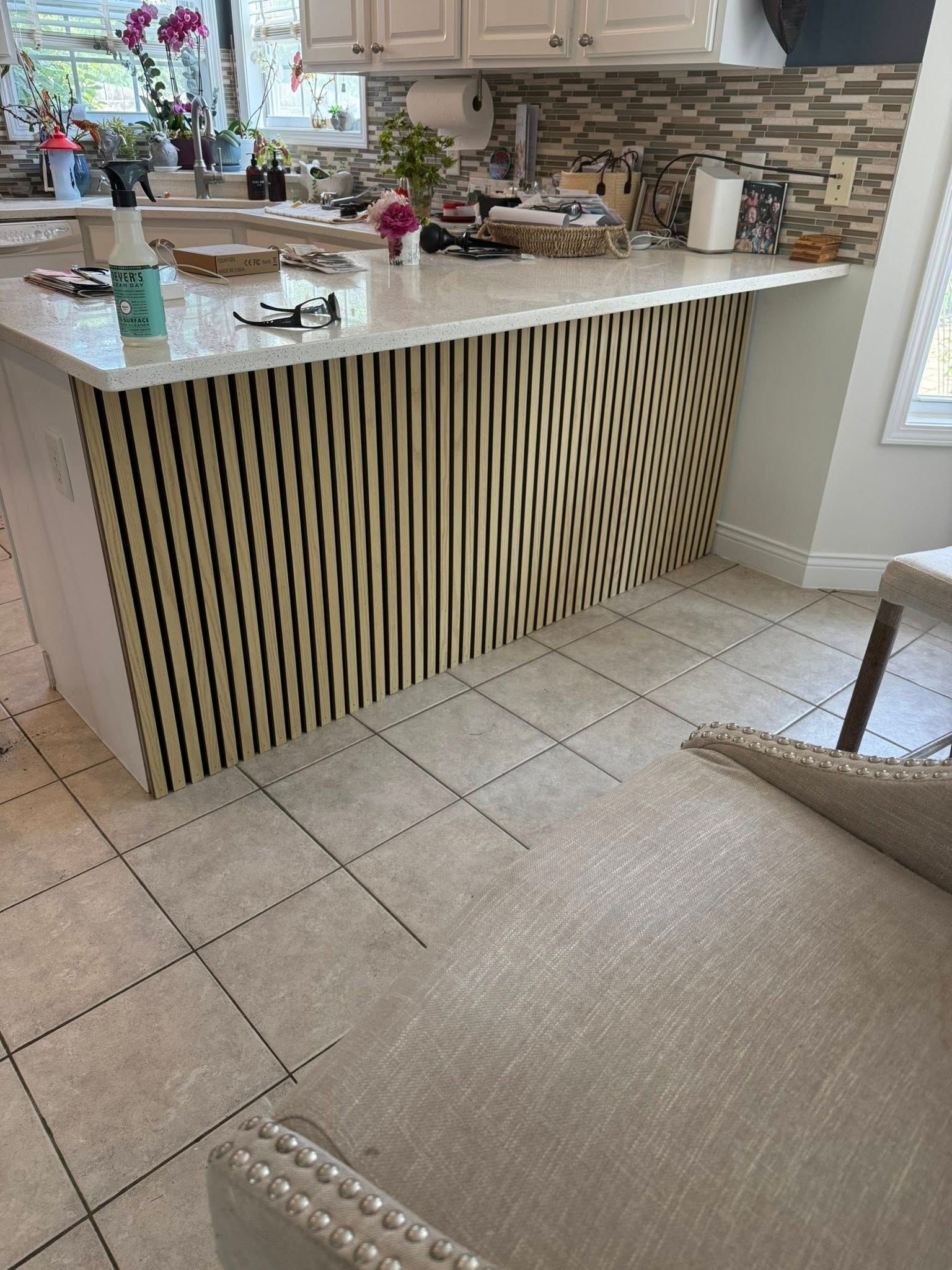 Kitchen island with wood slat design, white countertop, beige tile floor.