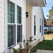 Exterior view of a house with multiple windows and a lamp. The siding is off-white.