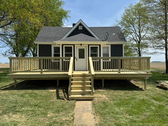 House with pergola under construction; new concrete patio, green grass, trees in background.