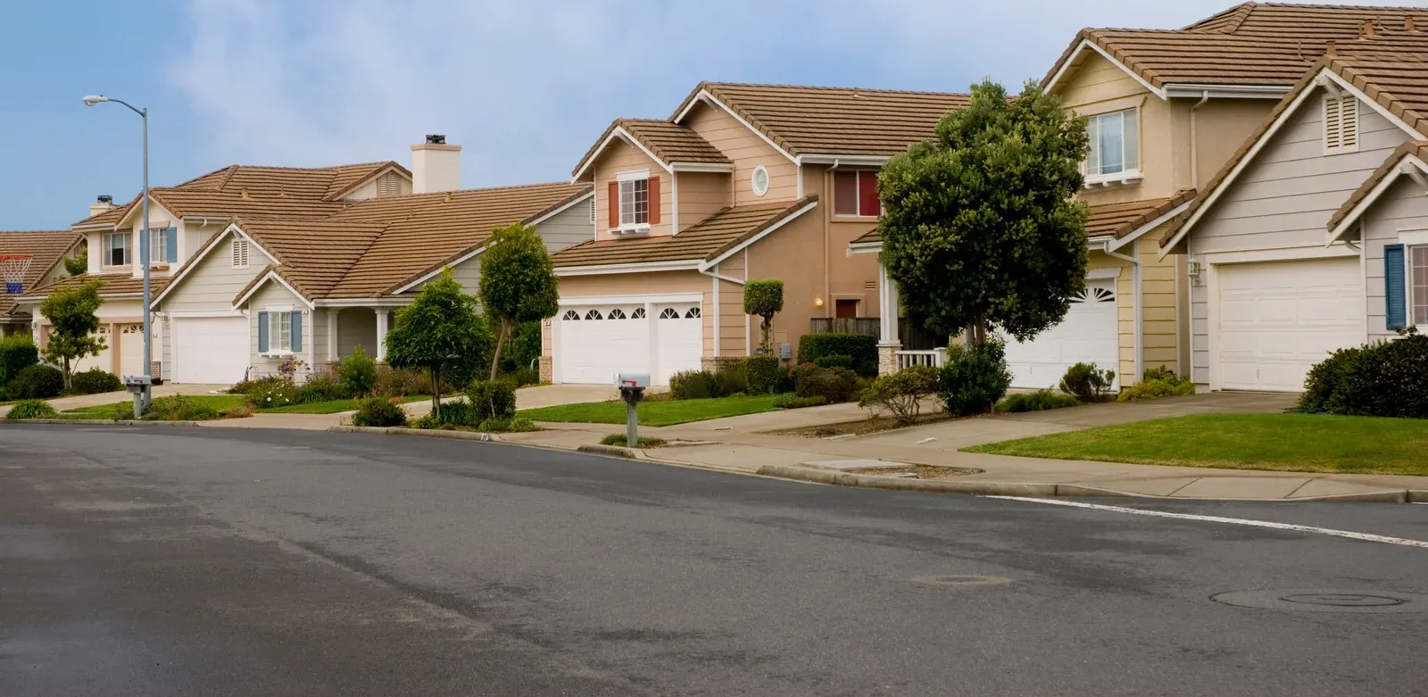 Wooden deck on concrete supports in grassy yard, blue sky, clouds.