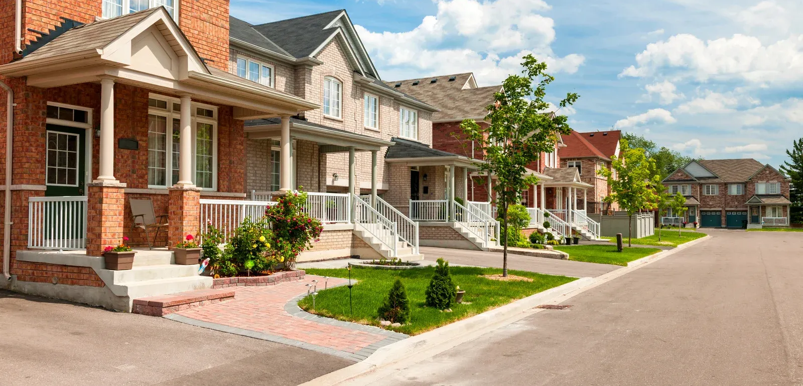 A wooden deck with stairs attached to a white house, on a grassy lawn.
