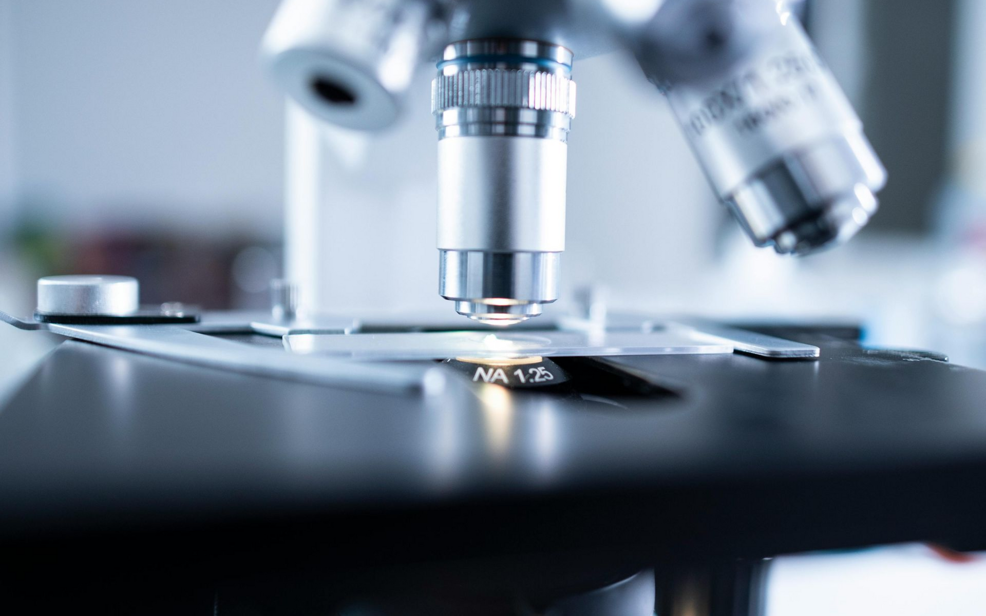 Microscope, up close, with a bright light, lab setting.