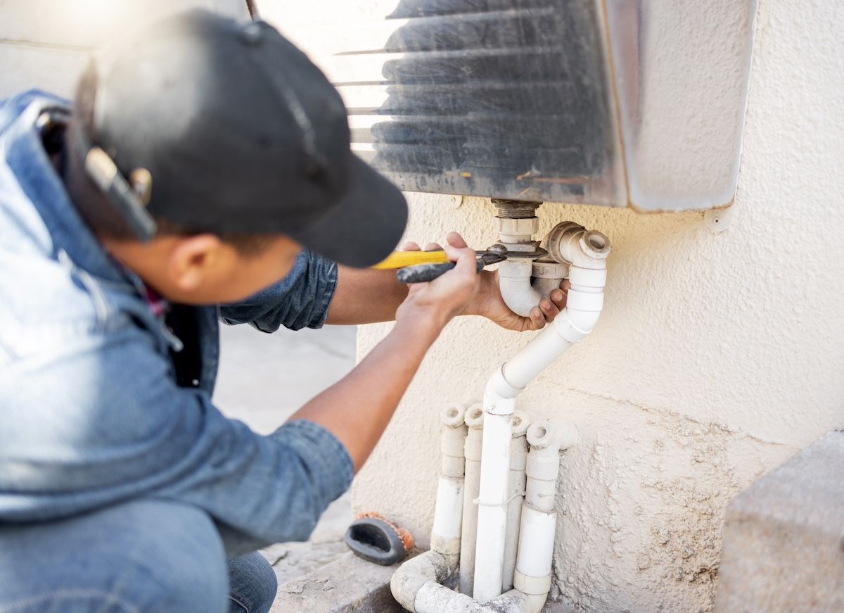 A Plumber Works on Fixing a PVC Pipe. Understand Who Manages Commercial Repairs With Lindner.