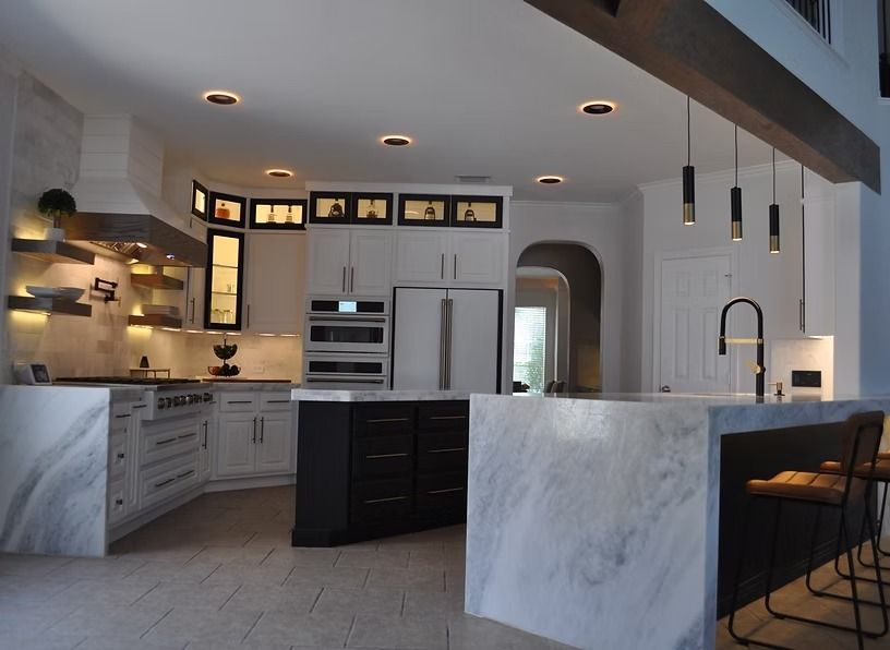 Modern kitchen with marble countertops, white cabinets, and dark island.