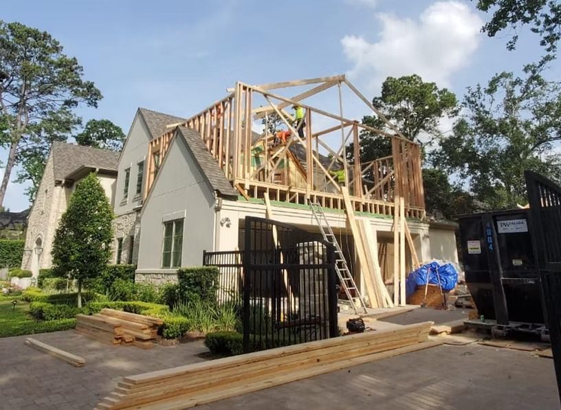 House under construction; framing of a second story addition, workers on site.