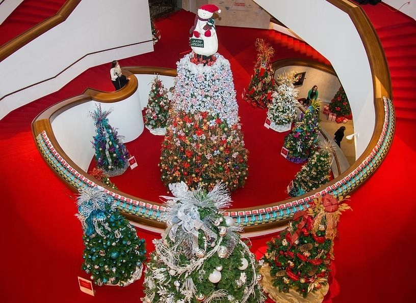 Christmas trees surrounding a large snowman on red carpet staircase.