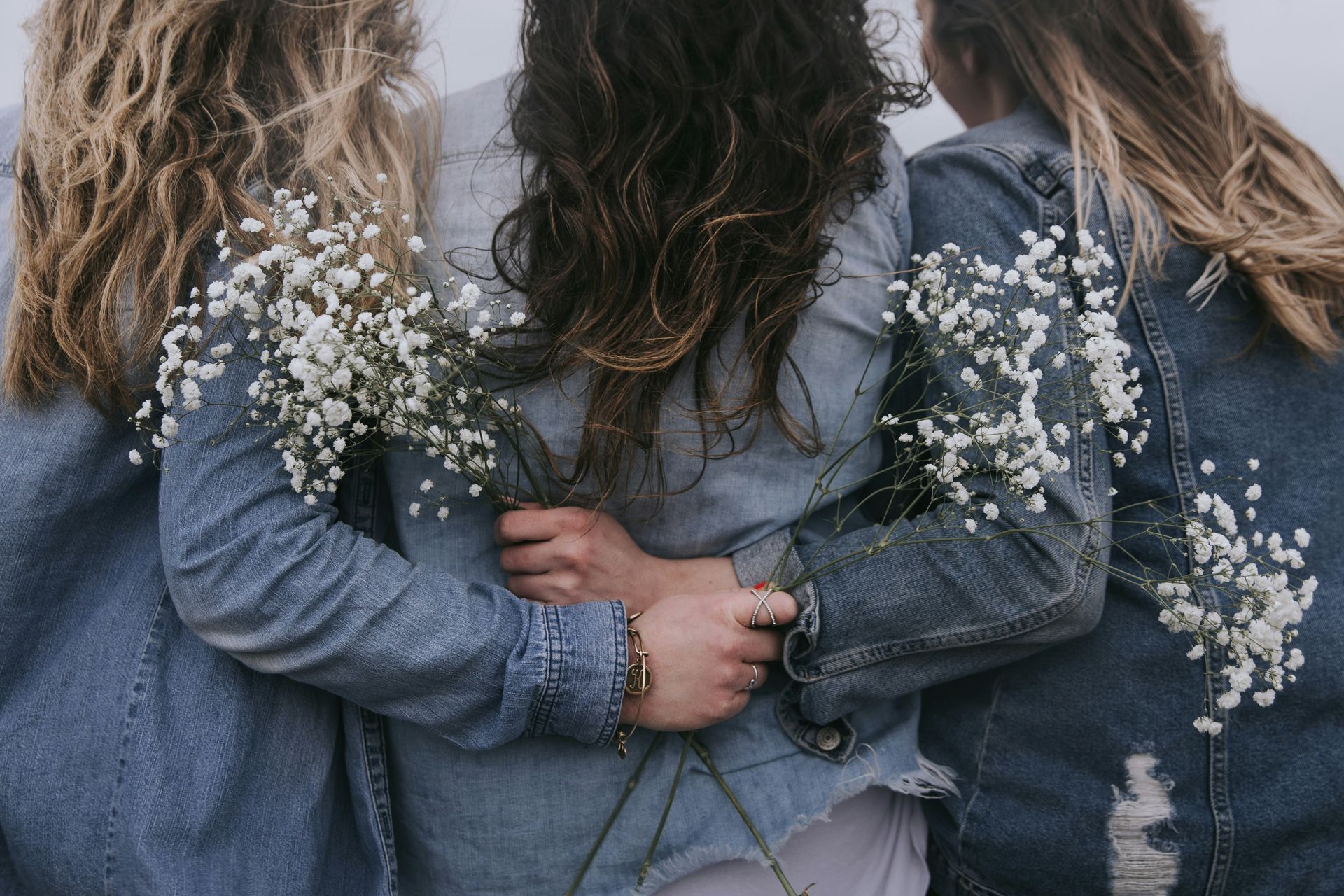 Three women hugging each other with baby 's breath on their jackets.