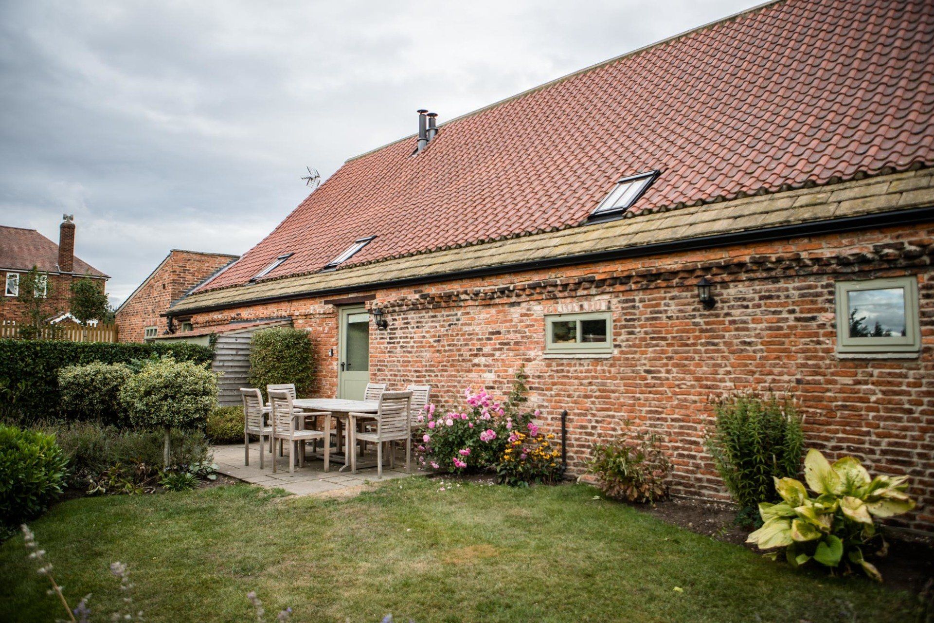There is a table and chairs in the backyard of a brick building.