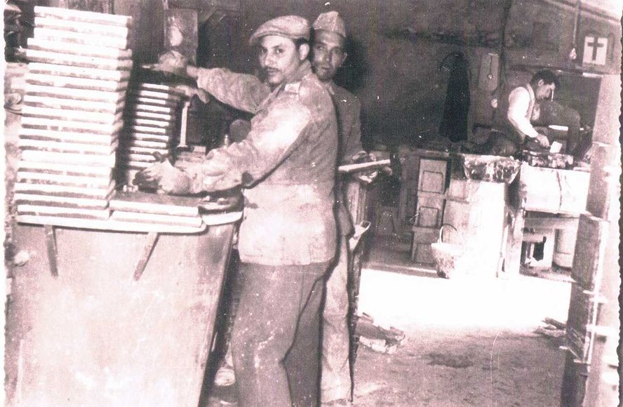 Tre uomini lavorano in un laboratorio. Due sono in piedi in primo piano, un altro lavora dietro.