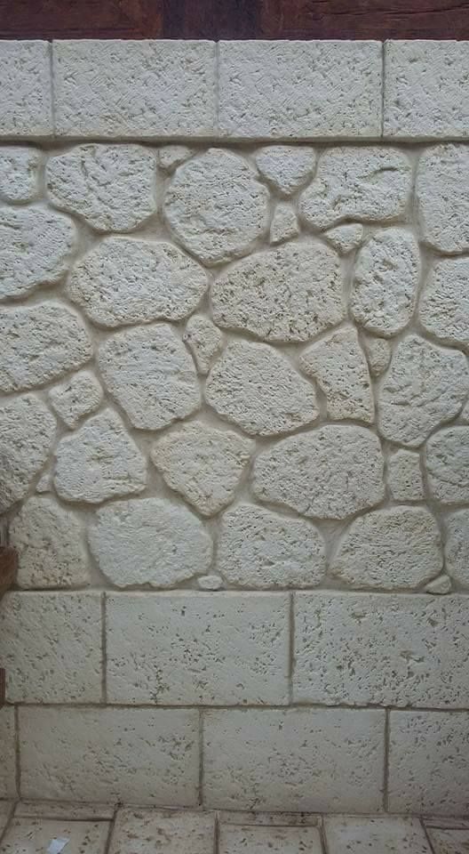 Una parete verticale caratterizzata da una facciata in pietra chiara e strutturata, con una sezione di pietre.