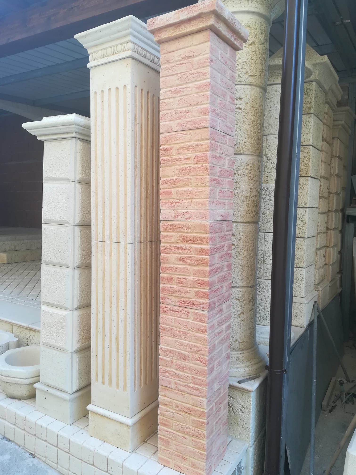 Numerose colonne e pilastri decorativi in ​​pietra, disposti verticalmente, presentano diverse texture e tonalità beige.