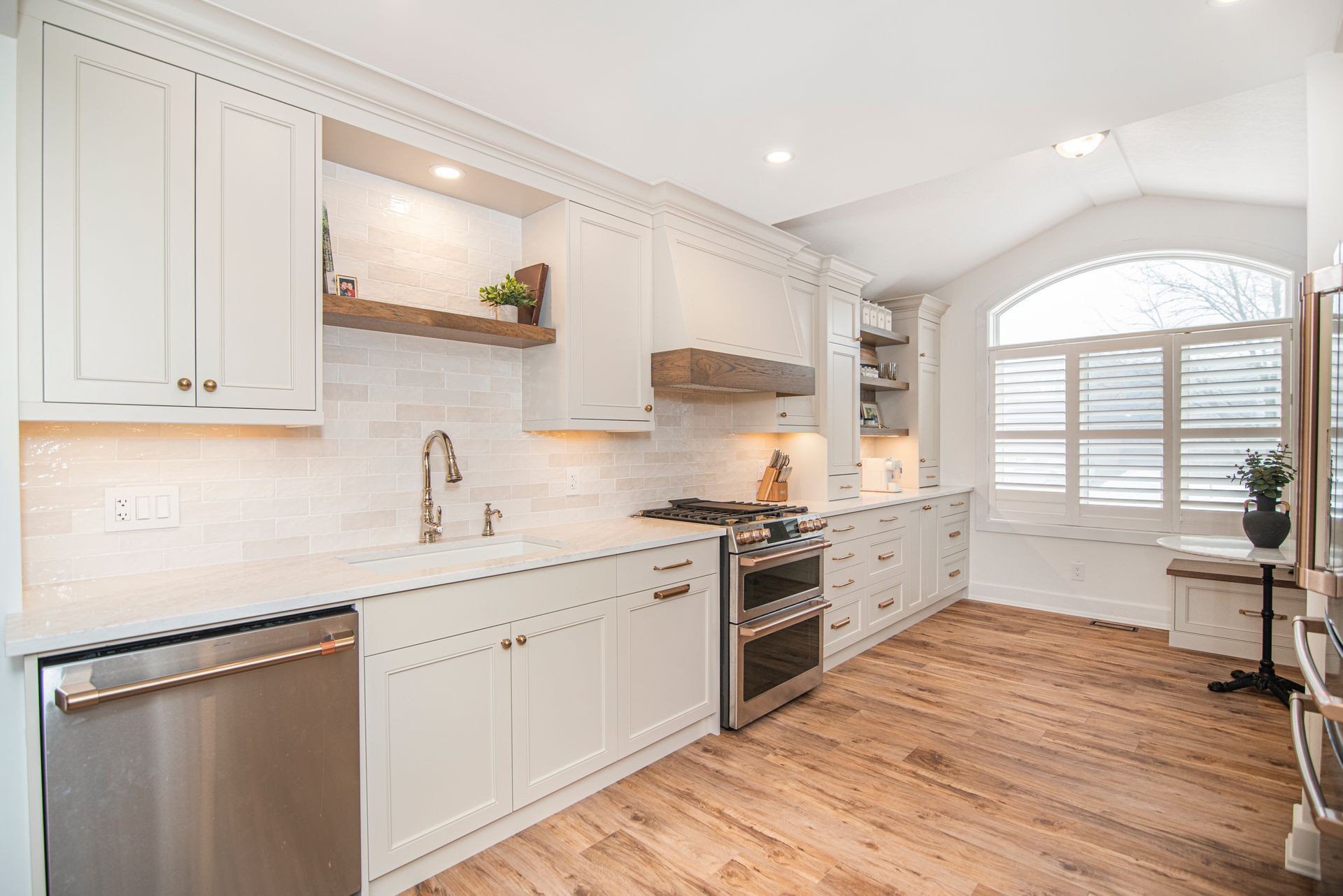 A kitchen with white cabinets , stainless steel appliances , and hardwood floors.