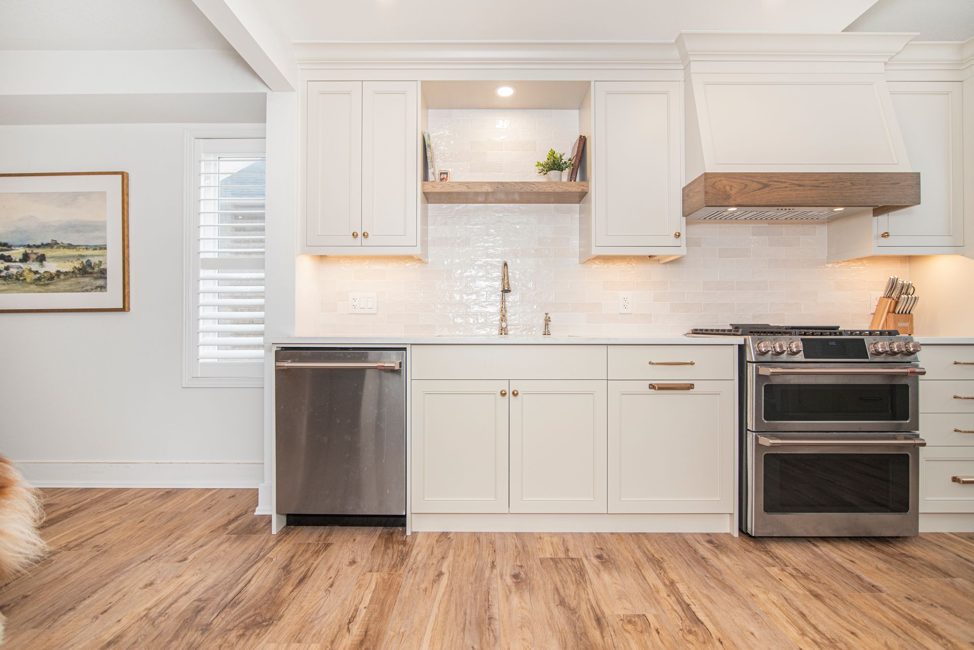 A kitchen with white cabinets , stainless steel appliances , and hardwood floors.