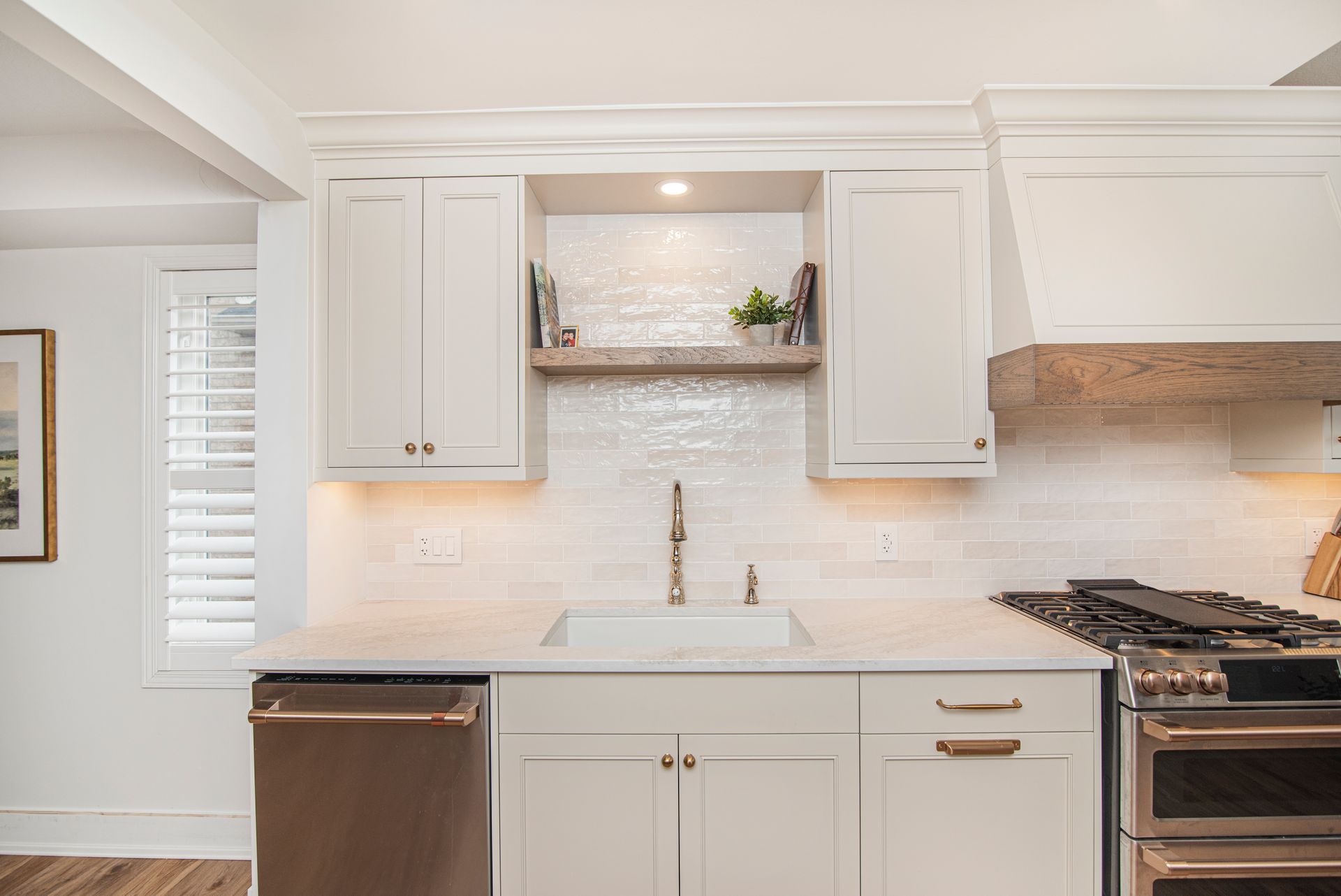 A kitchen with white cabinets , a sink , a stove , and a dishwasher.