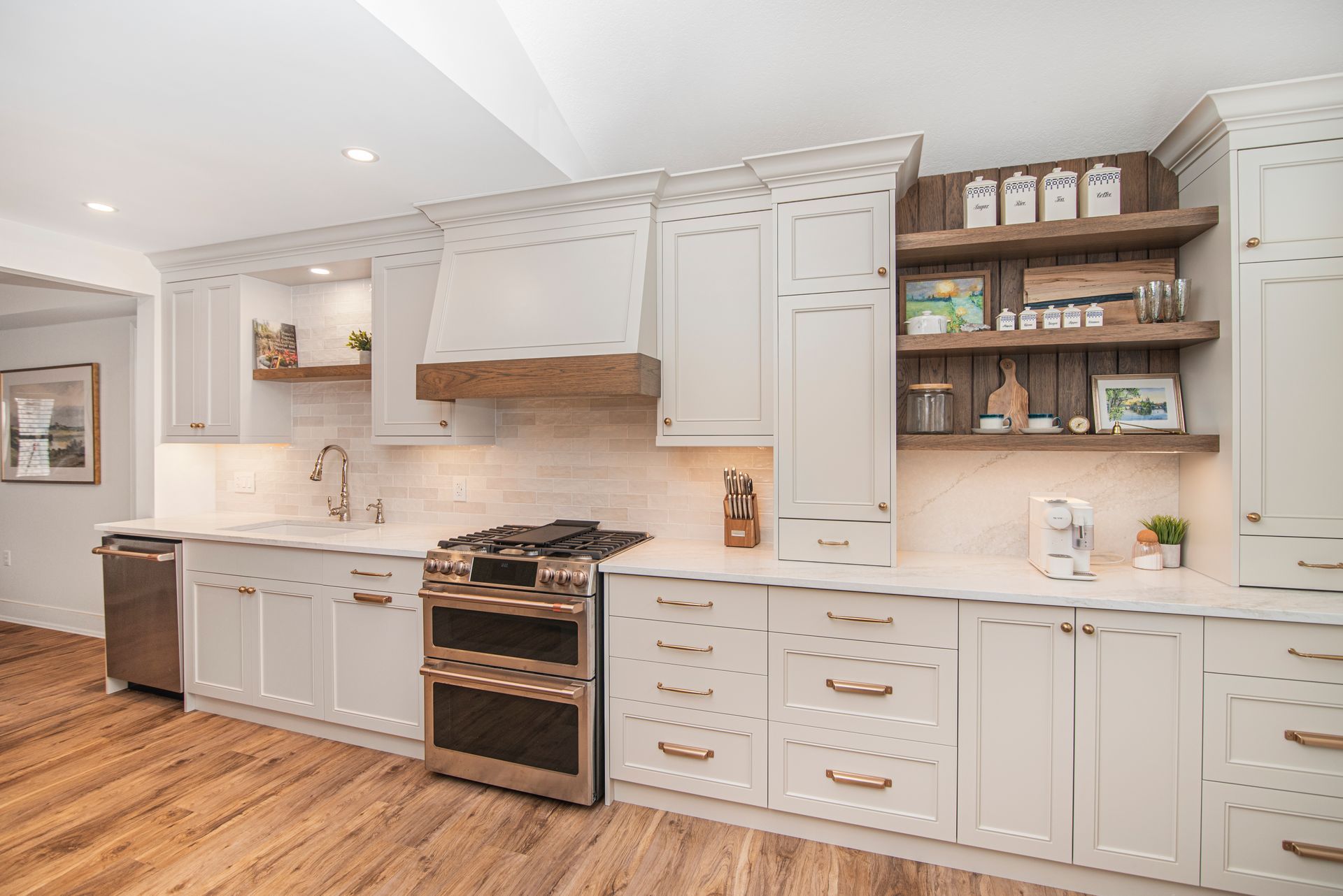 A kitchen with white cabinets , stainless steel appliances , and wooden floors.