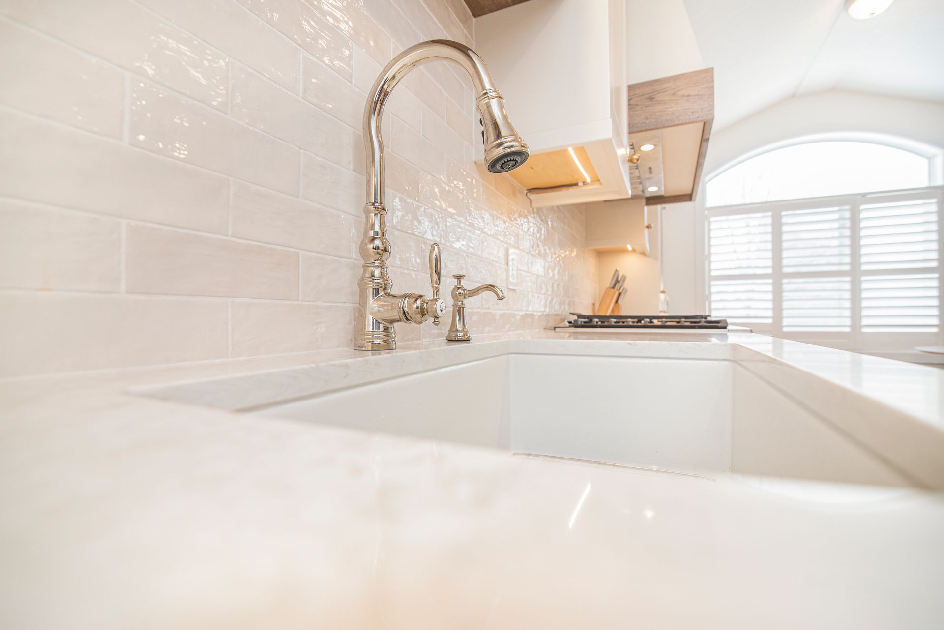 A kitchen sink with a faucet and a window in the background.