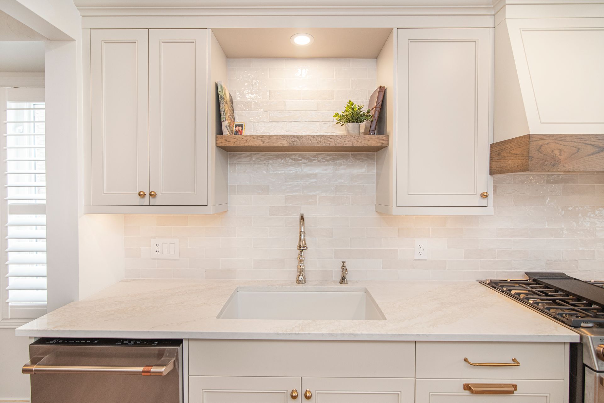 A kitchen with white cabinets , a sink , a stove , and a dishwasher.