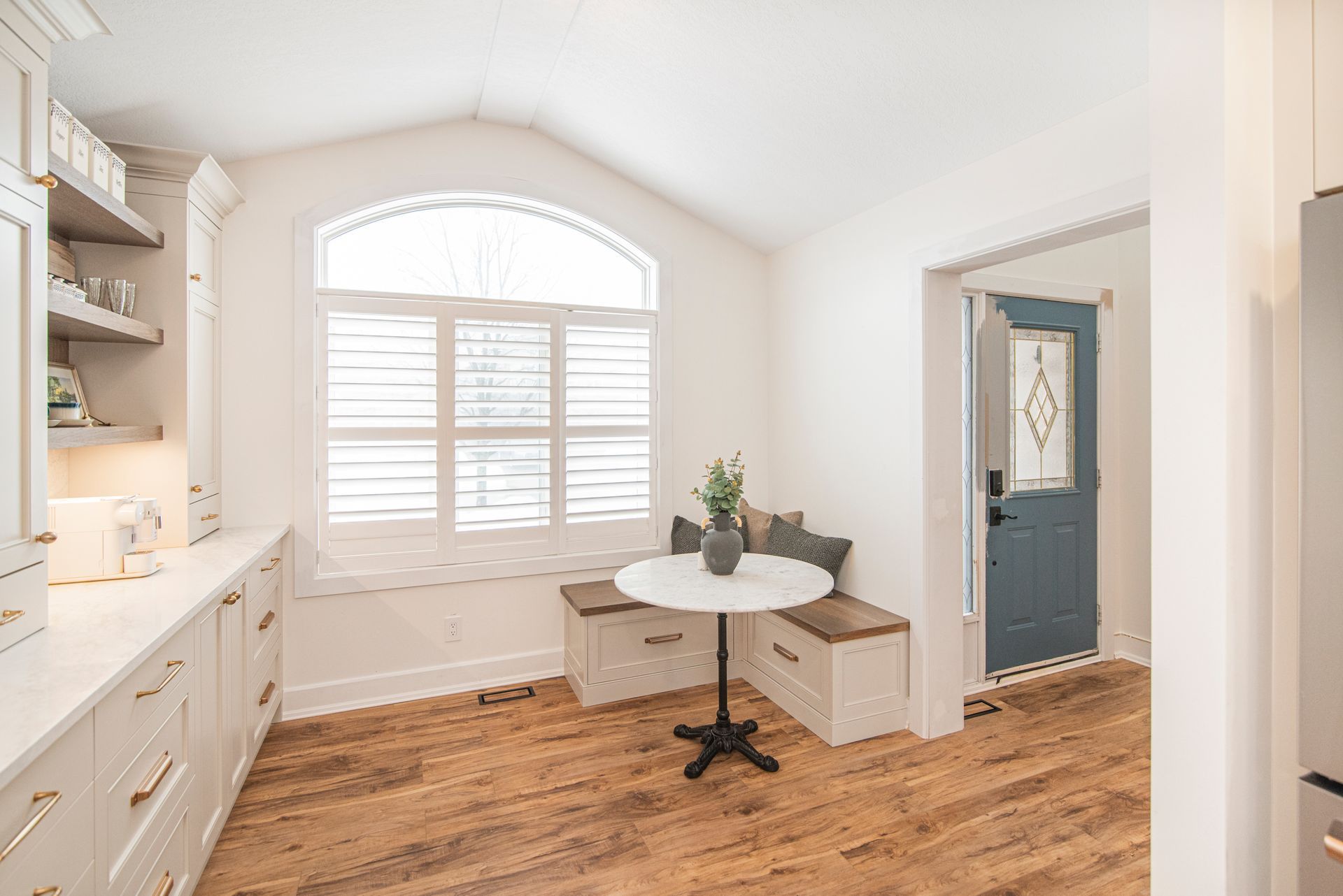 A kitchen with white cabinets , a stove , and a window.