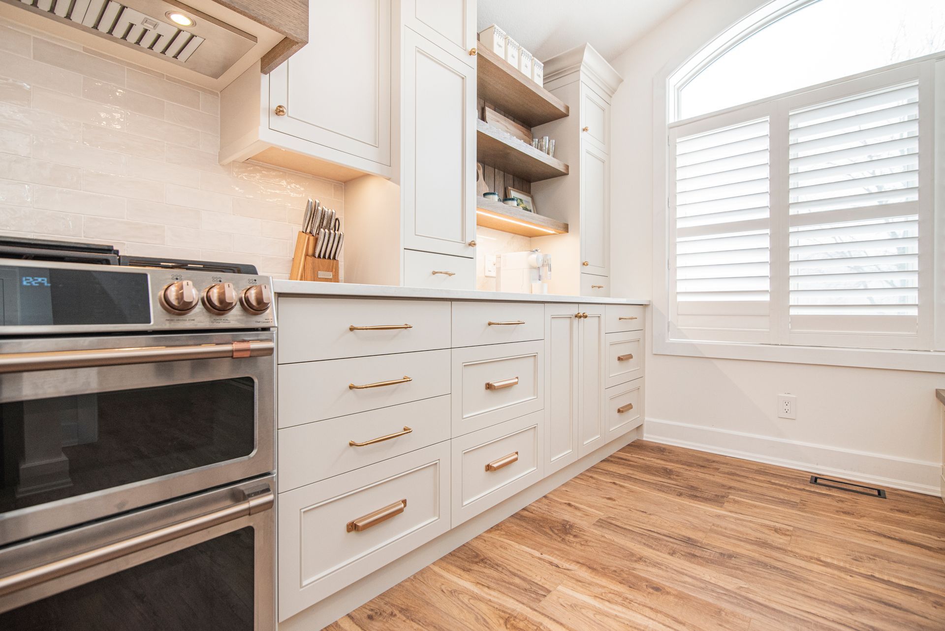 A kitchen with white cabinets , stainless steel appliances , and hardwood floors.