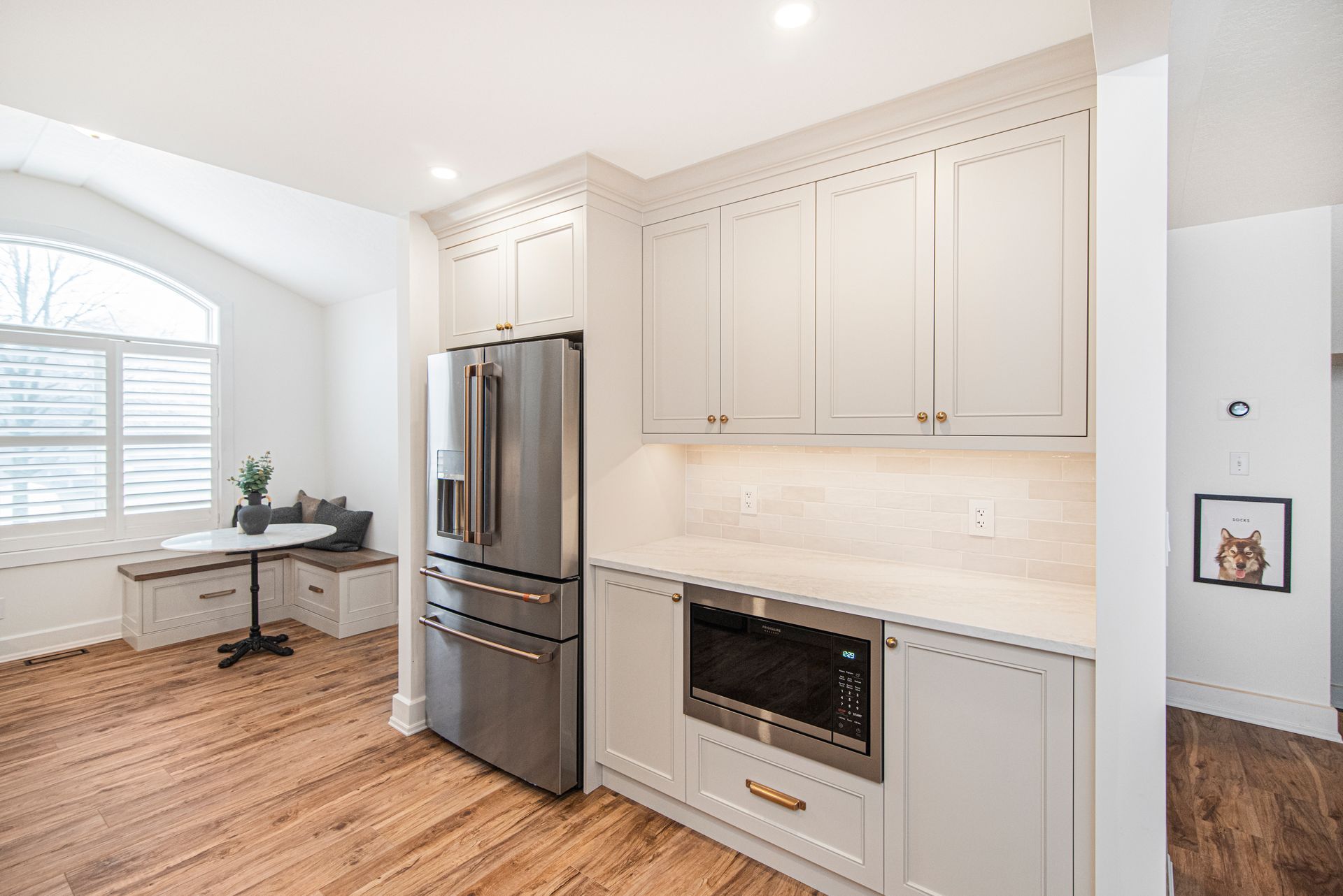 A kitchen with white cabinets , stainless steel appliances , a refrigerator and a microwave.