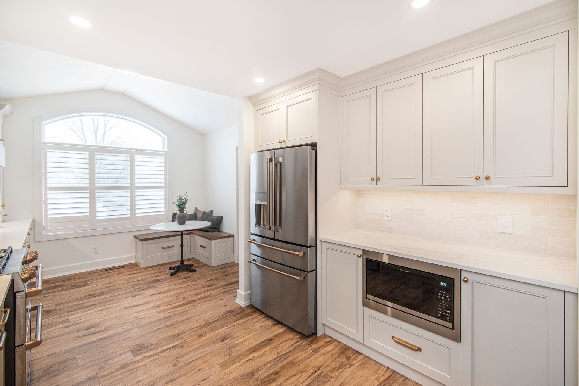 A kitchen with white cabinets , stainless steel appliances , and hardwood floors.