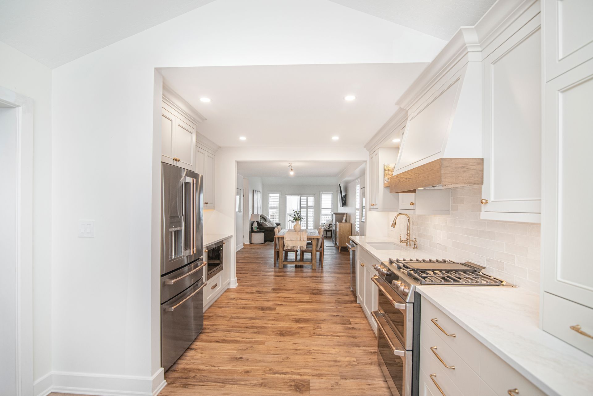 A kitchen with white cabinets , stainless steel appliances , and hardwood floors.