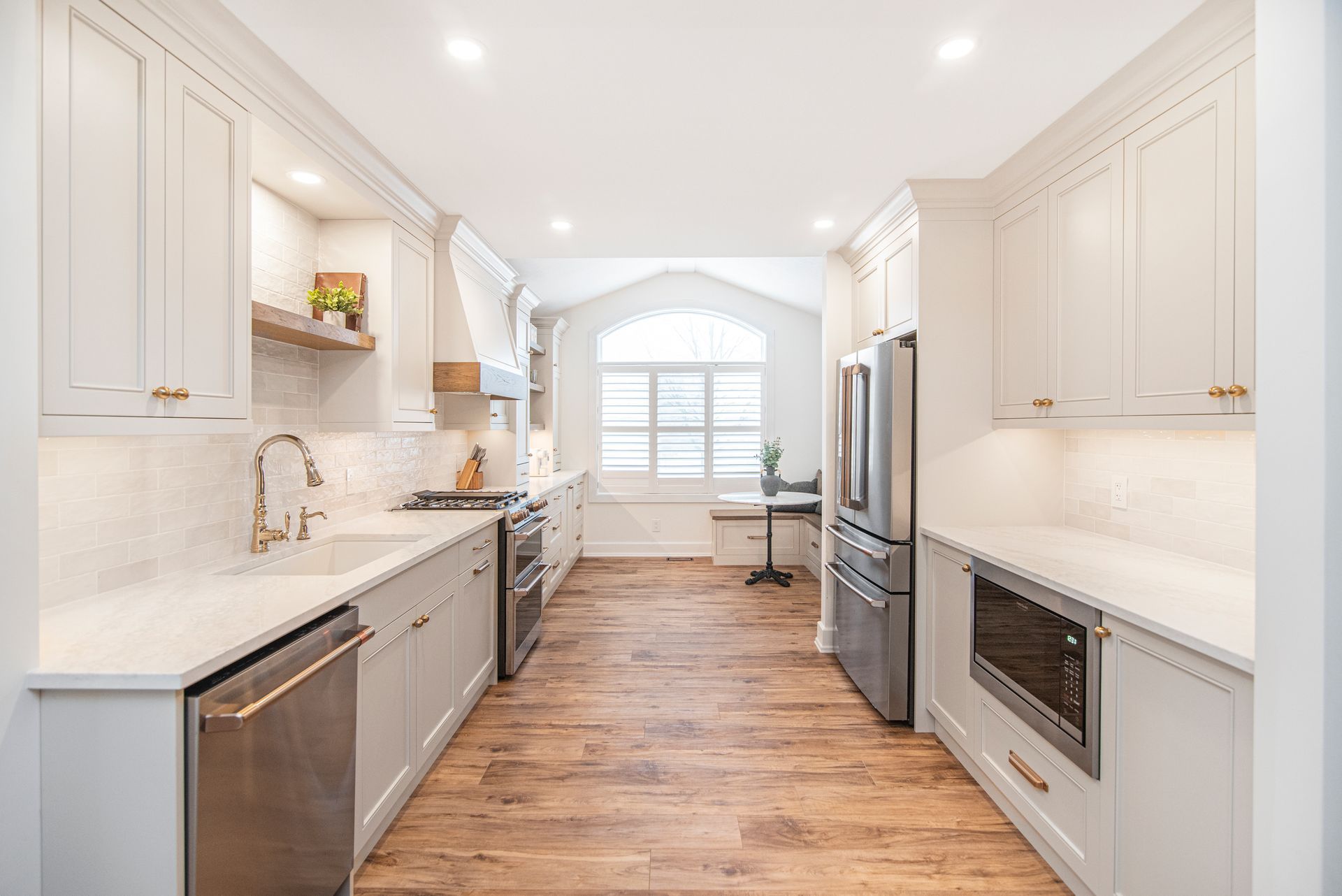 A kitchen with white cabinets , stainless steel appliances , and hardwood floors.