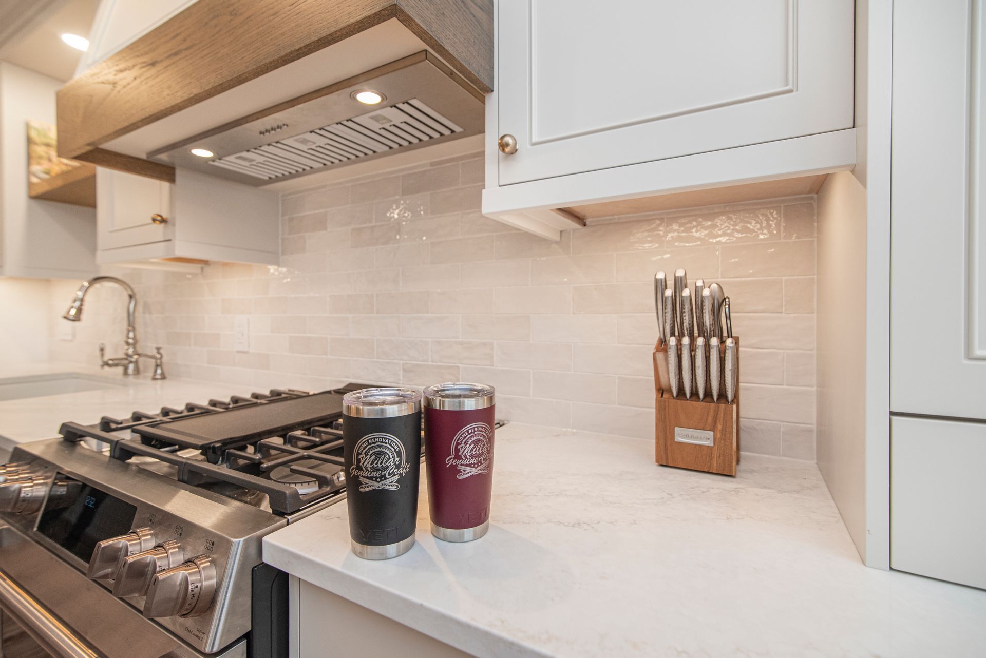 Two tumblers are sitting on a kitchen counter next to a stove.