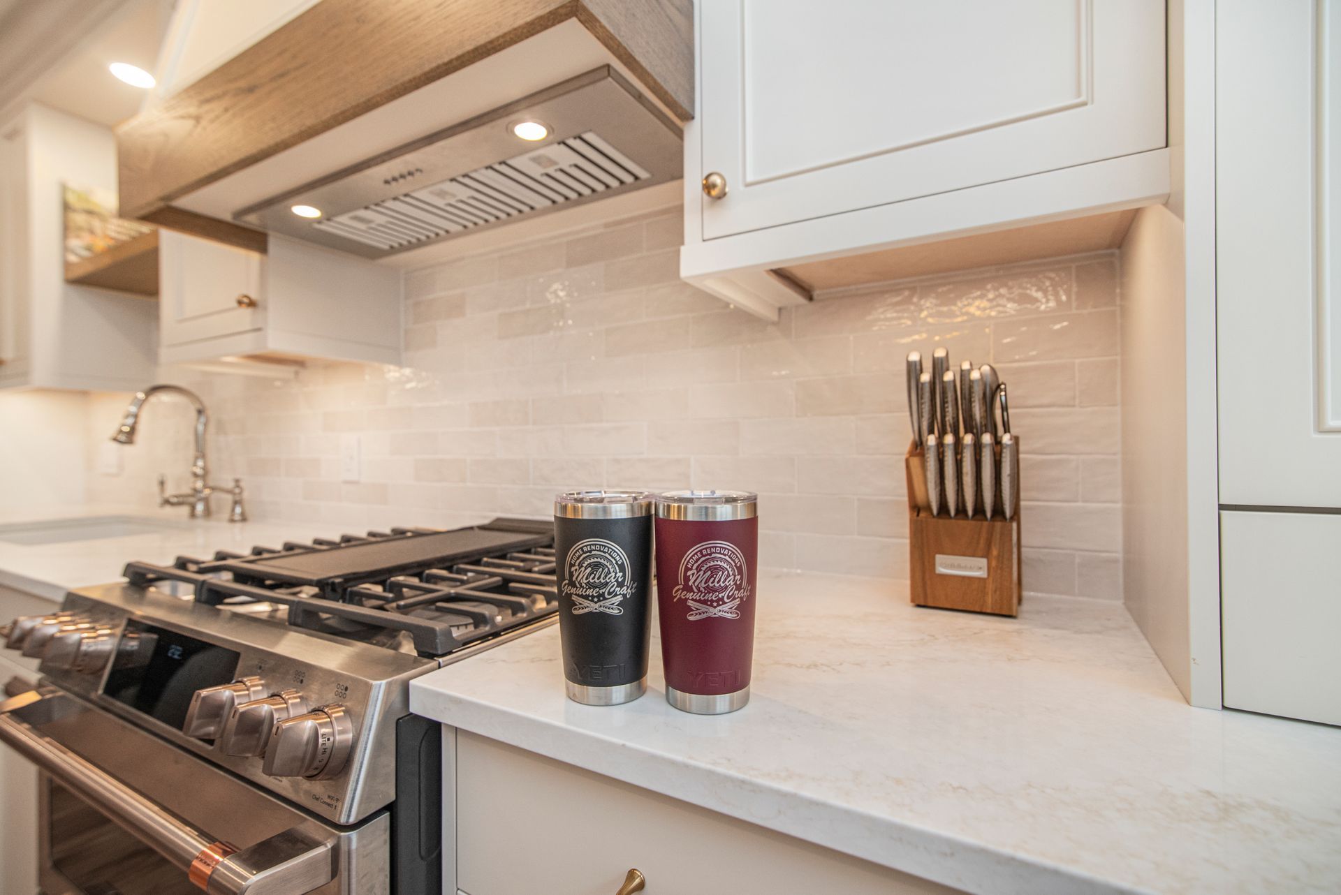 Two tumblers are sitting on a counter in a kitchen next to a stove.