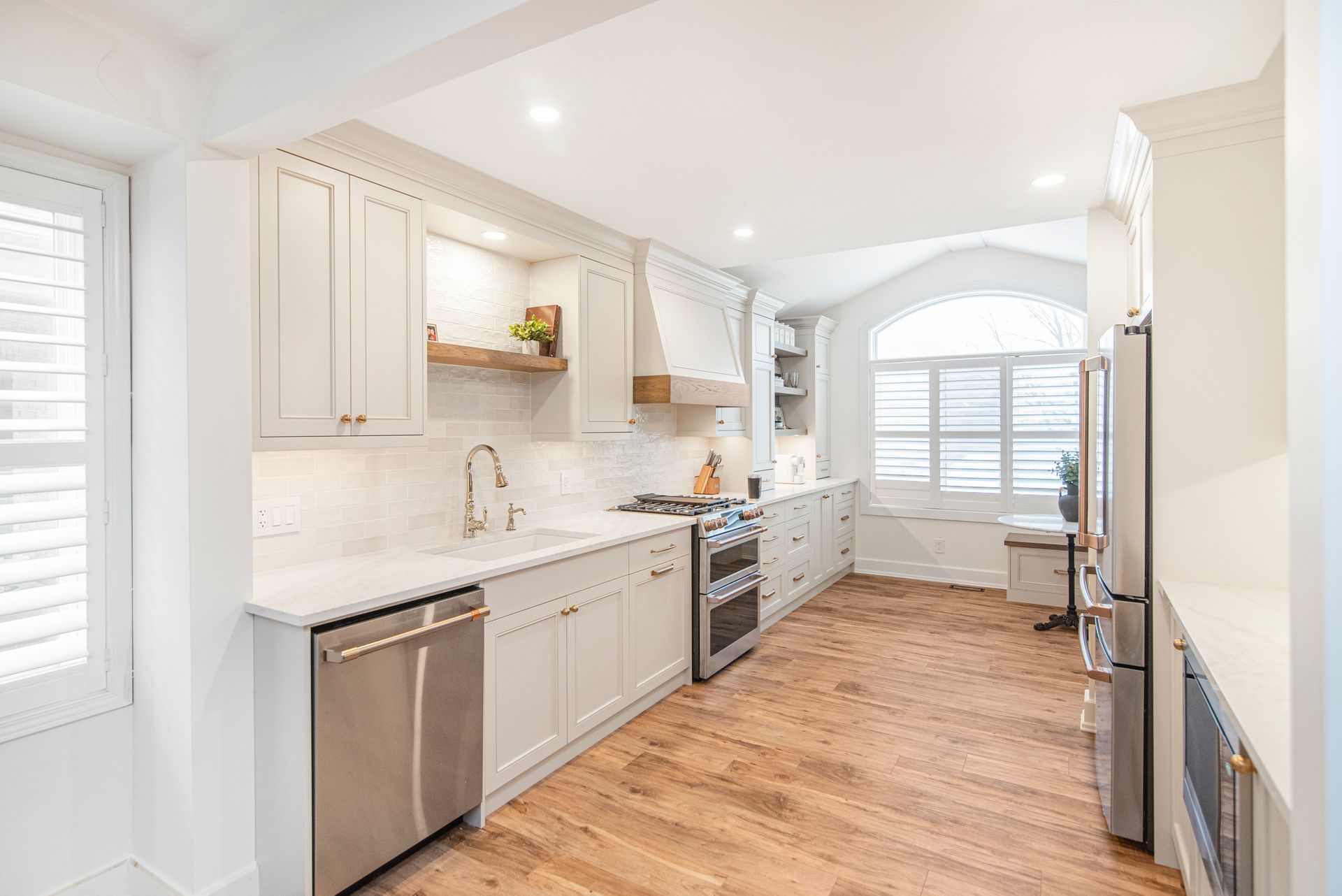 A kitchen with white cabinets , stainless steel appliances , and hardwood floors.