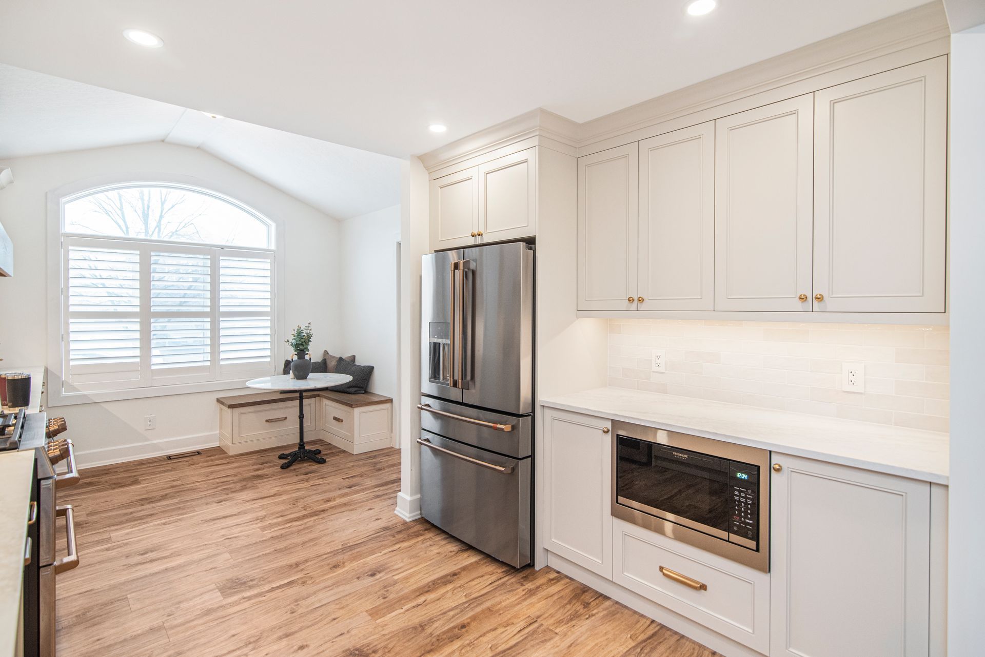 A kitchen with white cabinets , stainless steel appliances , and hardwood floors.
