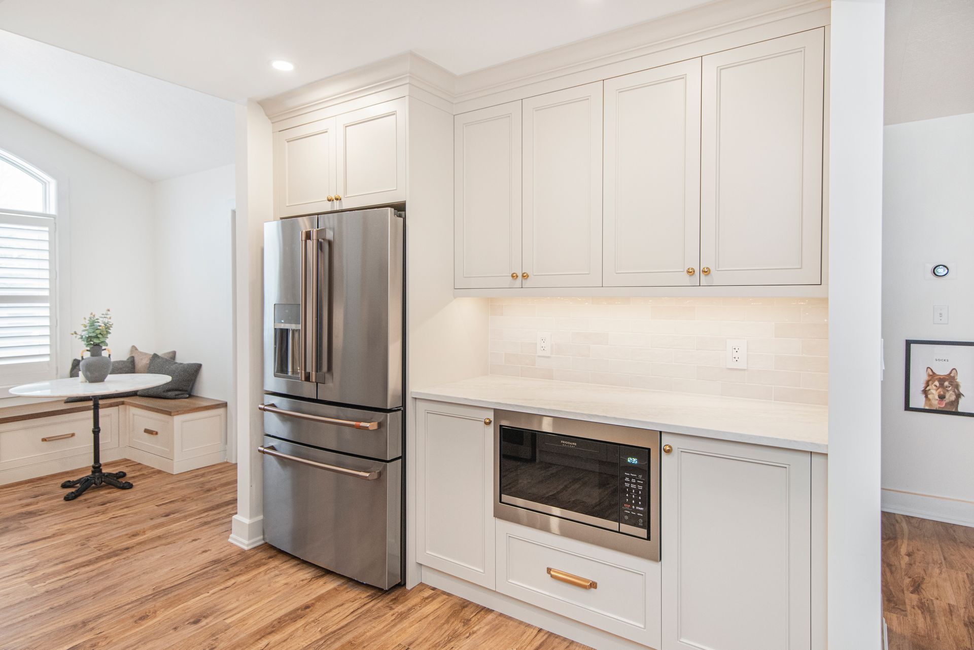 A kitchen with white cabinets , stainless steel appliances , a refrigerator and a microwave.