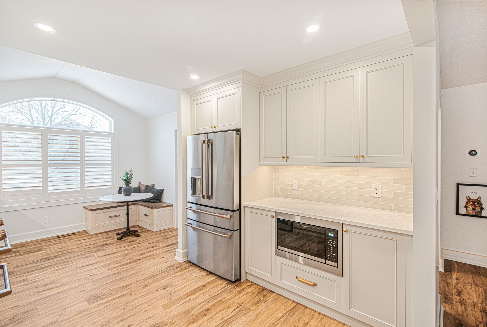 A kitchen with white cabinets , stainless steel appliances , and hardwood floors.